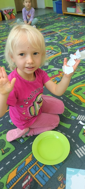 Dziewczynka pokazuje ręce. Do jednej jest przyczepiony papier ponieważ jest mokra. Druga ręka jest sucha i czysta
