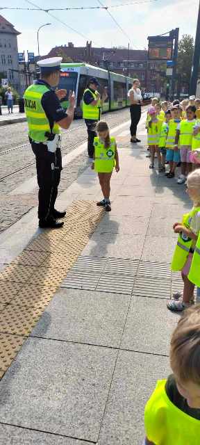 Przed przejściem policjant tłumaczy dzieciom jak należy się zachować.