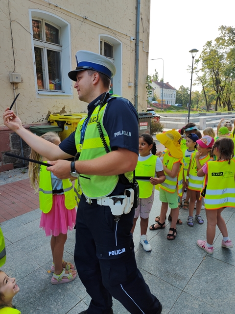 Policjant zakłada opaski odblaskowe na nadgarstki dzieci