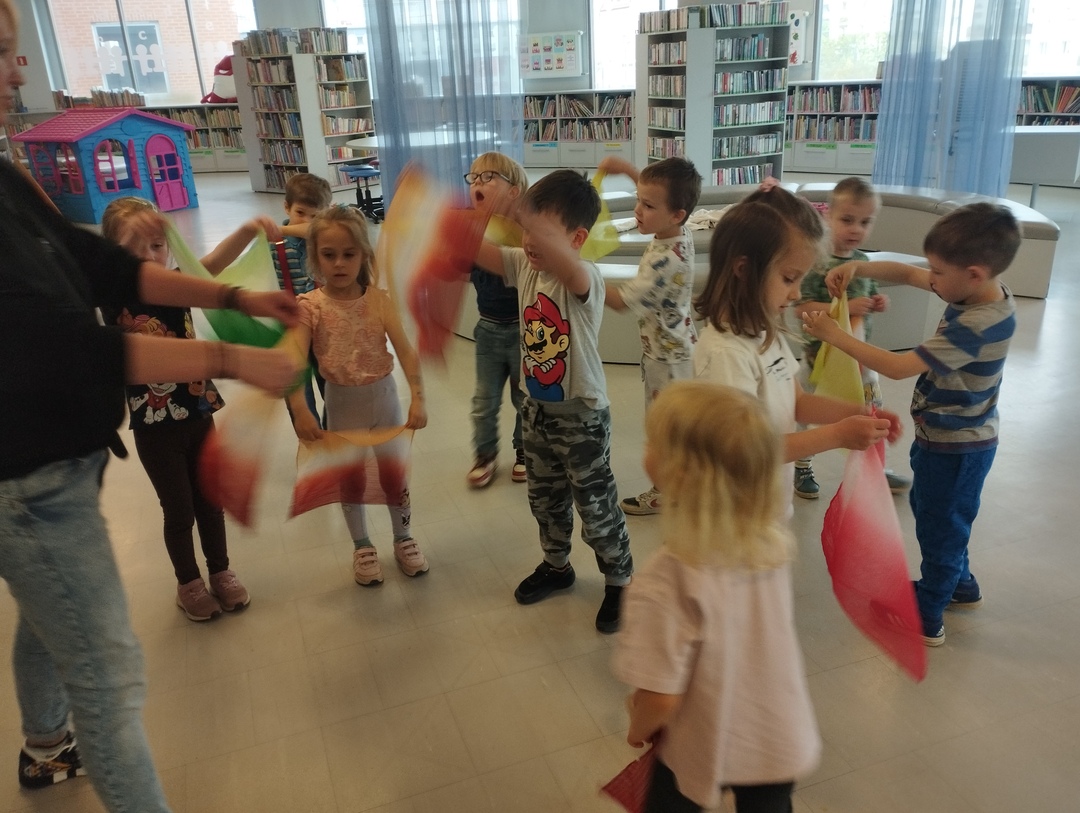 Dzieci w rozsypce biorą udział w zabawie z chustkami.