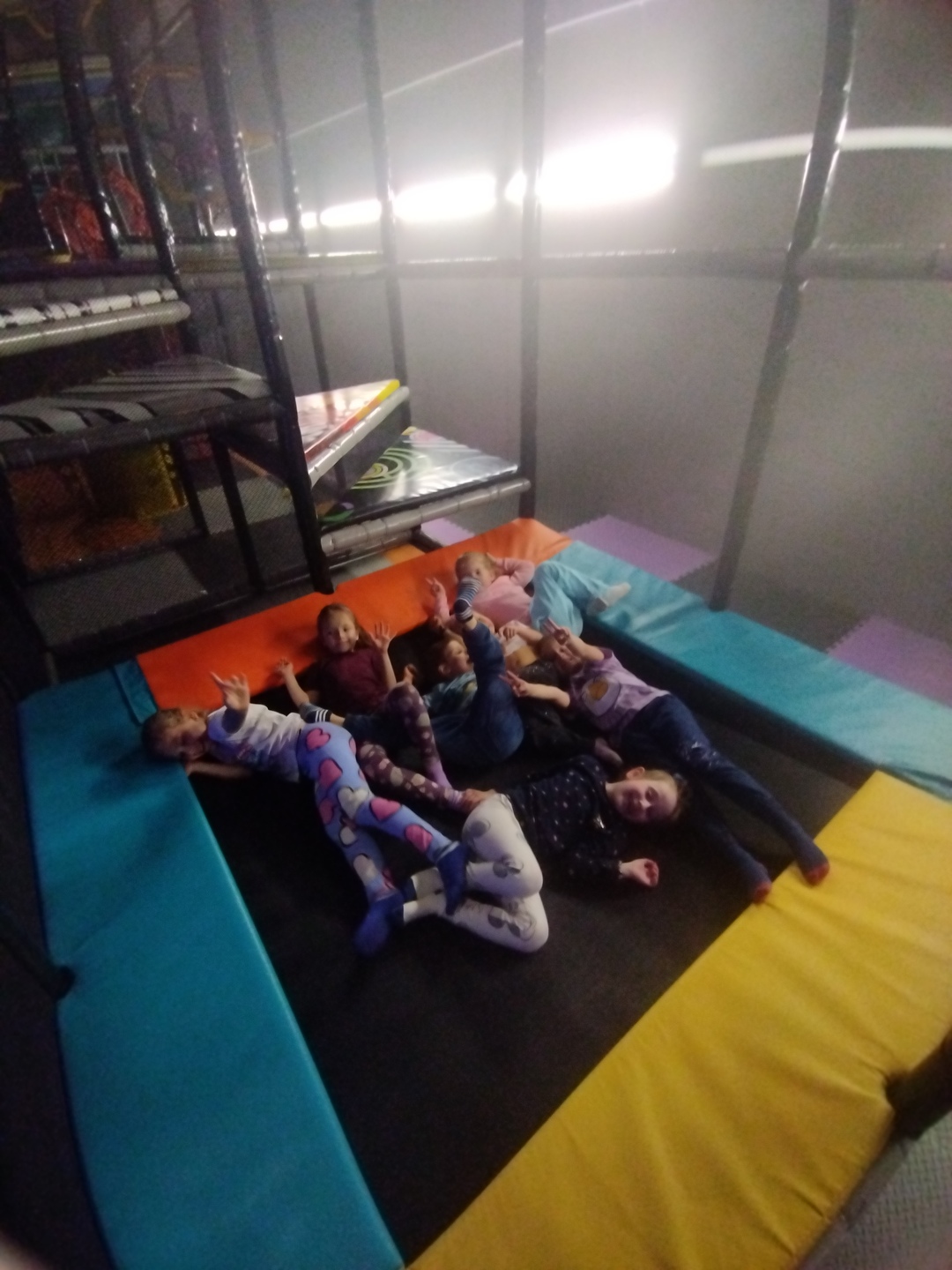 Dzieci leżą na trampolinie i pozują do zdjęcia.